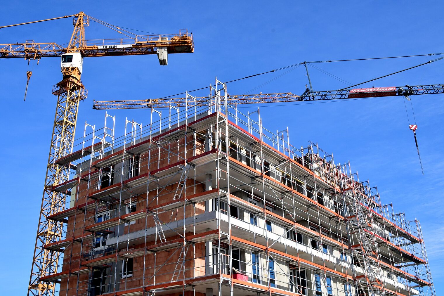 Baustelle eines mehrstöckigen Wohnhauses mit zwei Kränen