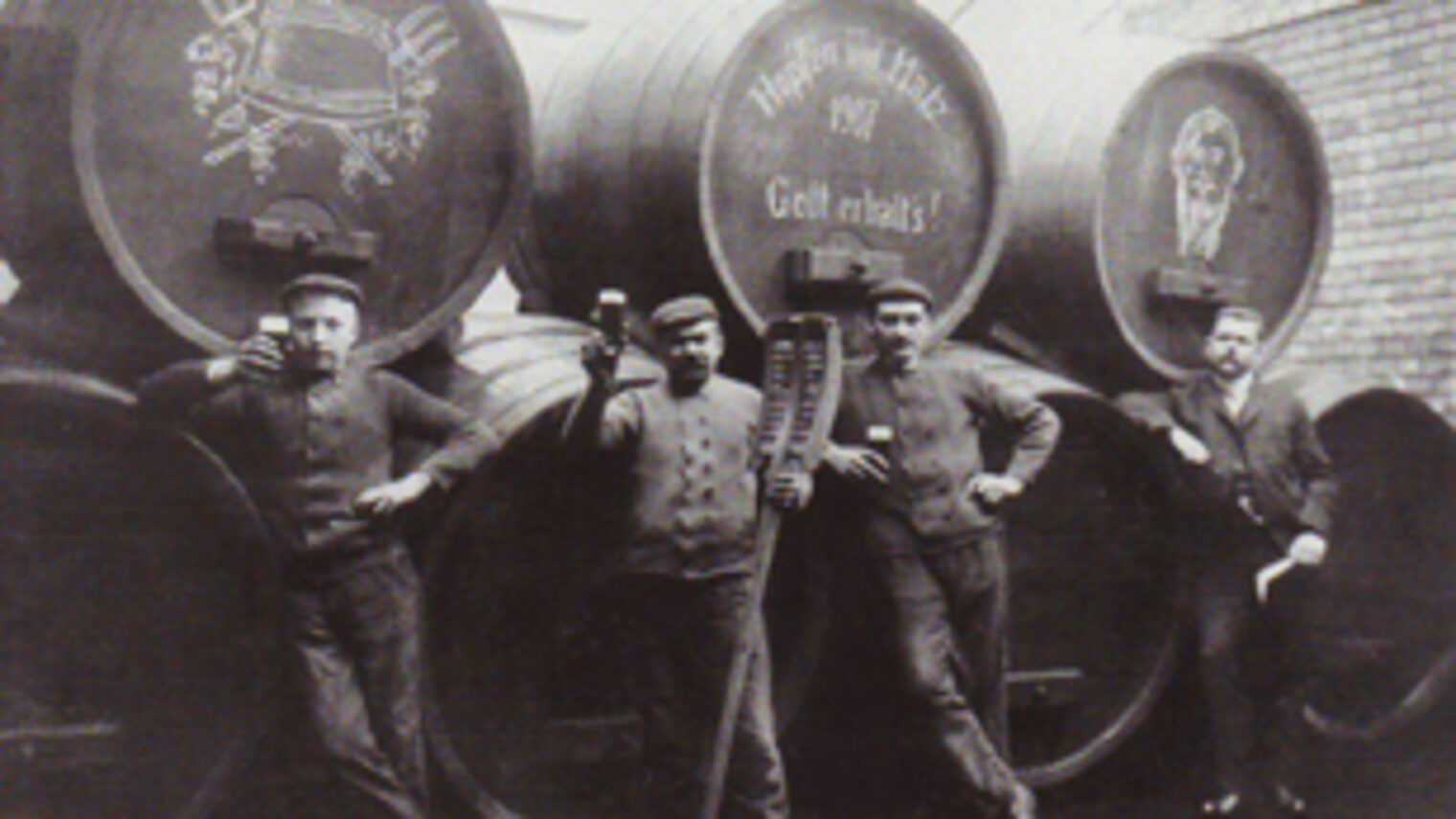 Historisches Foto von Brauern, die vor Bierfässern stehen.