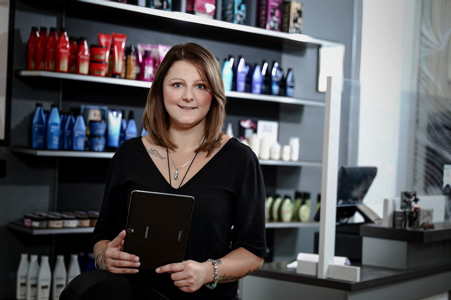 Unternehmerin steht mit Tablet in der Hand in Friseursalon.