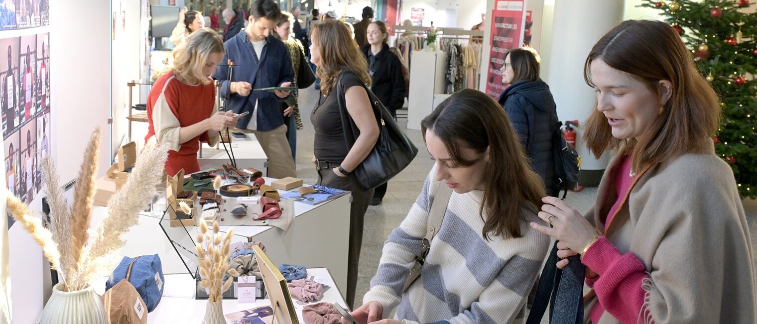Zwei junge Besucherinnen der Unikate-Ausstellung schauen sich Kunsthandwerk-Objekte an.