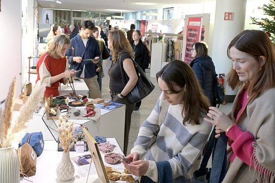Zwei junge Besucherinnen der Unikate-Ausstellung schauen sich Kunsthandwerk-Objekte an.